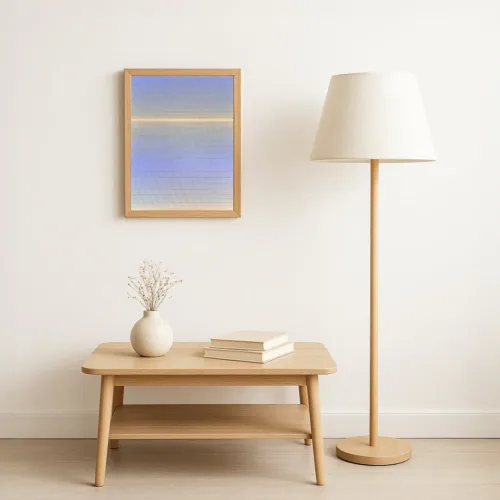 The artwork displayed in a minimalist interior setting with light wood flooring, a matching lamp and table, and neutral walls. The painting’s soft colours bring a calm and luminous presence to the space.